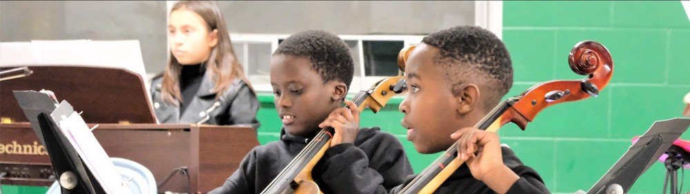 Two black boys playing cellos with a green background